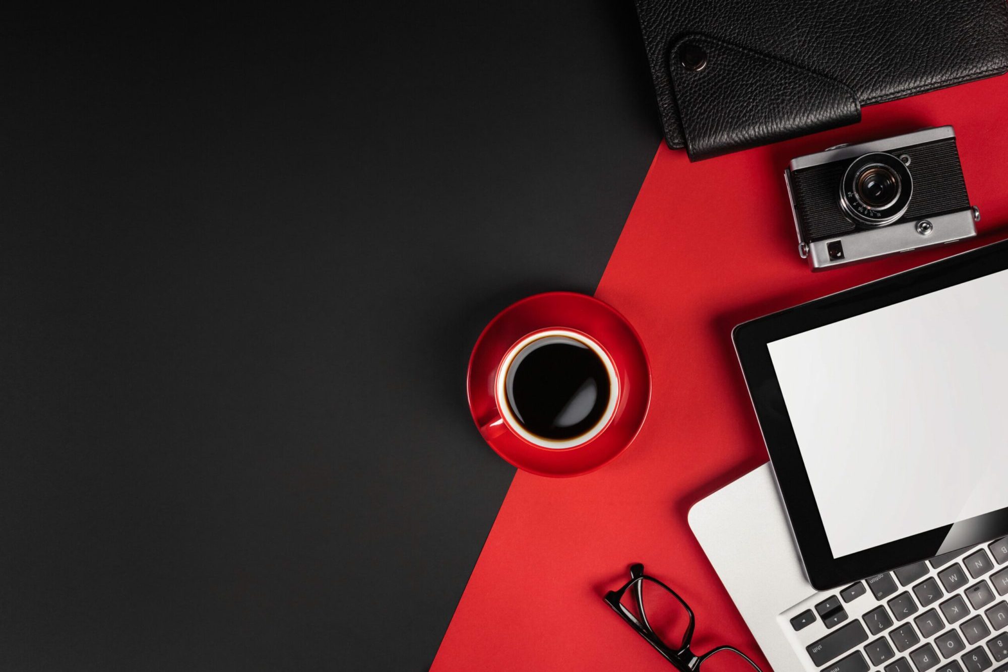 Laptop on a black desktop with a cup of coffee, a phone and a wi-fi sign, work in social networks. Top view.